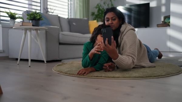 An Indian mother lying on floor and having fun with her little son at home.