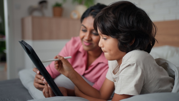 An Indian mother using tablet with her little son and having fun at home.