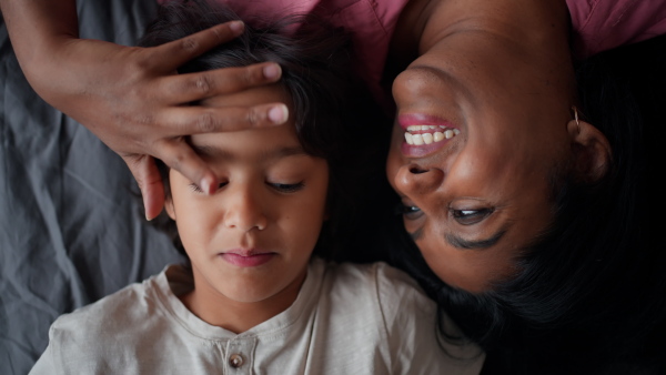 An overhead view of indian mother lying on bed with her little son at home.