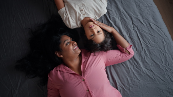 An overhead view of indian mother lying on bed with her little son at home.