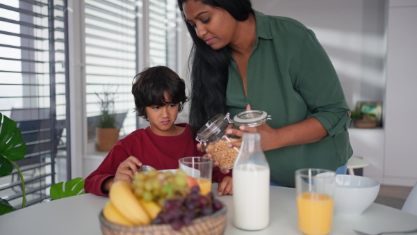 A happy little boy having breakfast with his mother at home.