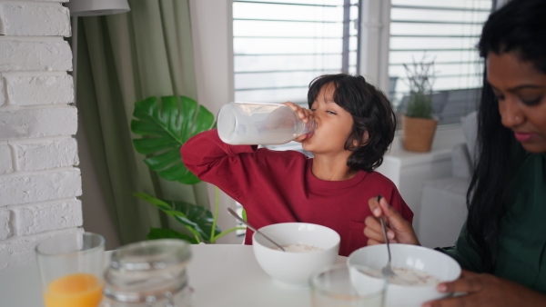 A happy little boy having breakfast with his mother at home.