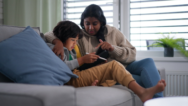 An Indian mother using tablet with her little son and having fun at home.