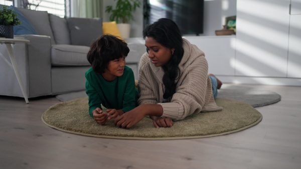 An Indian mother lying on floor and having fun with her little son at home.