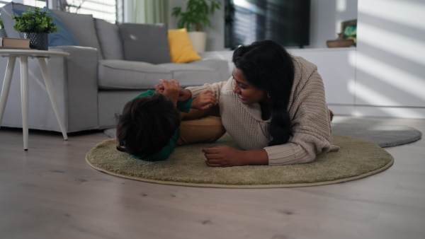 An Indian mother lying on floor and having fun with her little son at home.