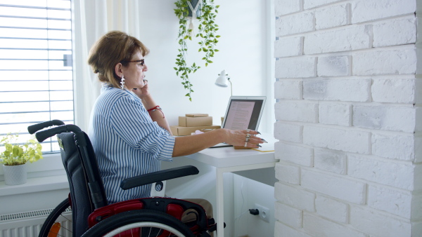 A disabled mature woman at home, working. Home office and leg amputee concept.