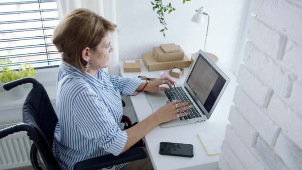 A disabled mature woman at home, working. Home office and leg amputee concept.