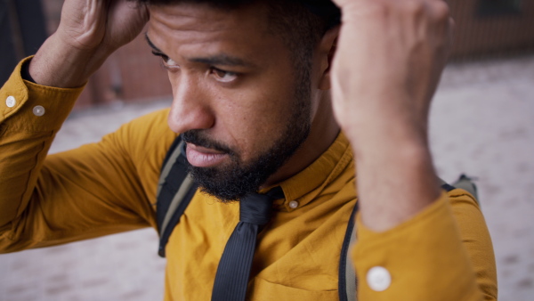 A close-up of young man commuter putting on cycling helmet.