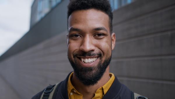 A close-up of young African-american man looking at camera in city.