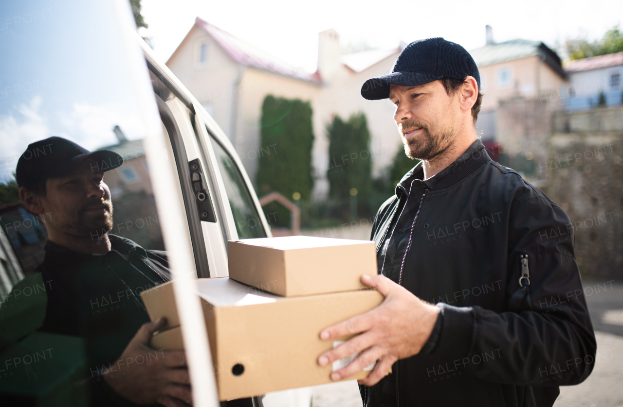 Side view of delivery man courier delivering parcel box in town. Copy space.