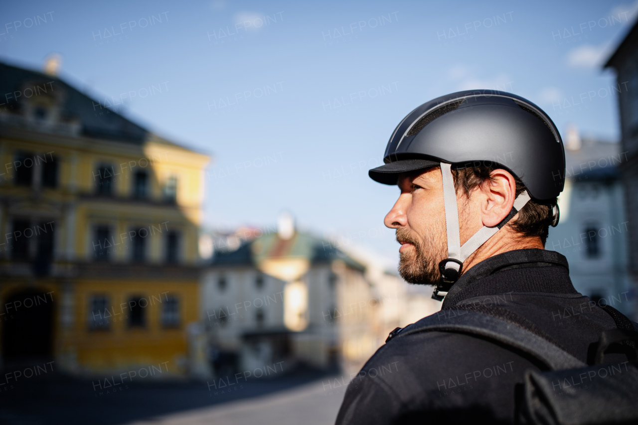 Delivery man courier with bicycle helmet standing in town.