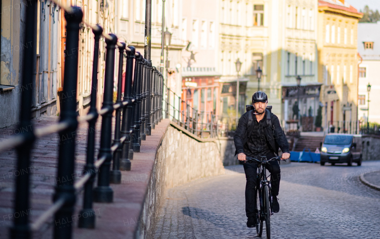 Front view of delivery man courier with bicycle cycling in small town.