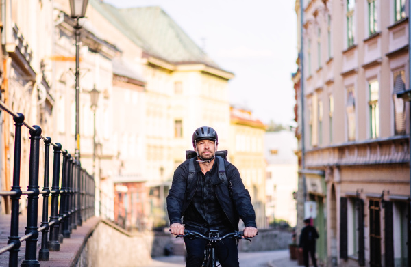 Front view of delivery man courier with bicycle cycling in small town.