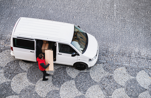 An aerial view of delivery man courier with face mask delivering parcel box in town.