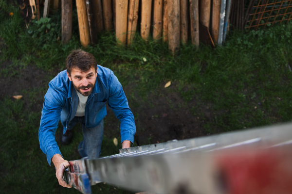 A high angle view of mature man climbing up the ladder