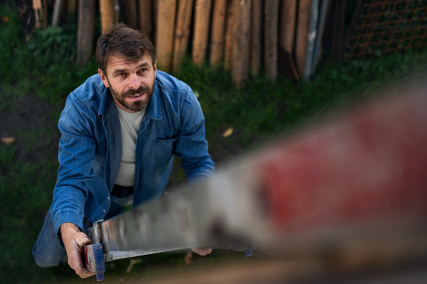 A high angle view of mature man climbing up the ladder