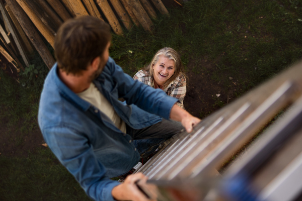 A high angle view of mature man climbing up the ladder