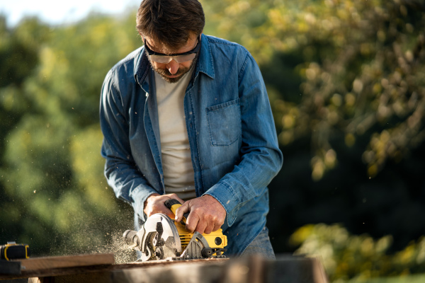 A craftsman working with circular saw at construction site