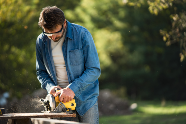 A craftsman working with circular saw at construction site