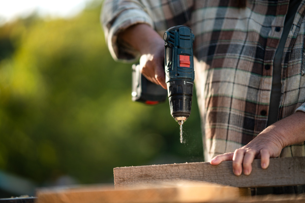 A close-up of handy female carpenter working in carpentry diy workshop outdoors