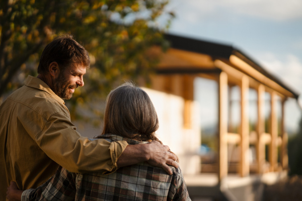 A mature couple looking at their new house under construction, planning future and dreaming.