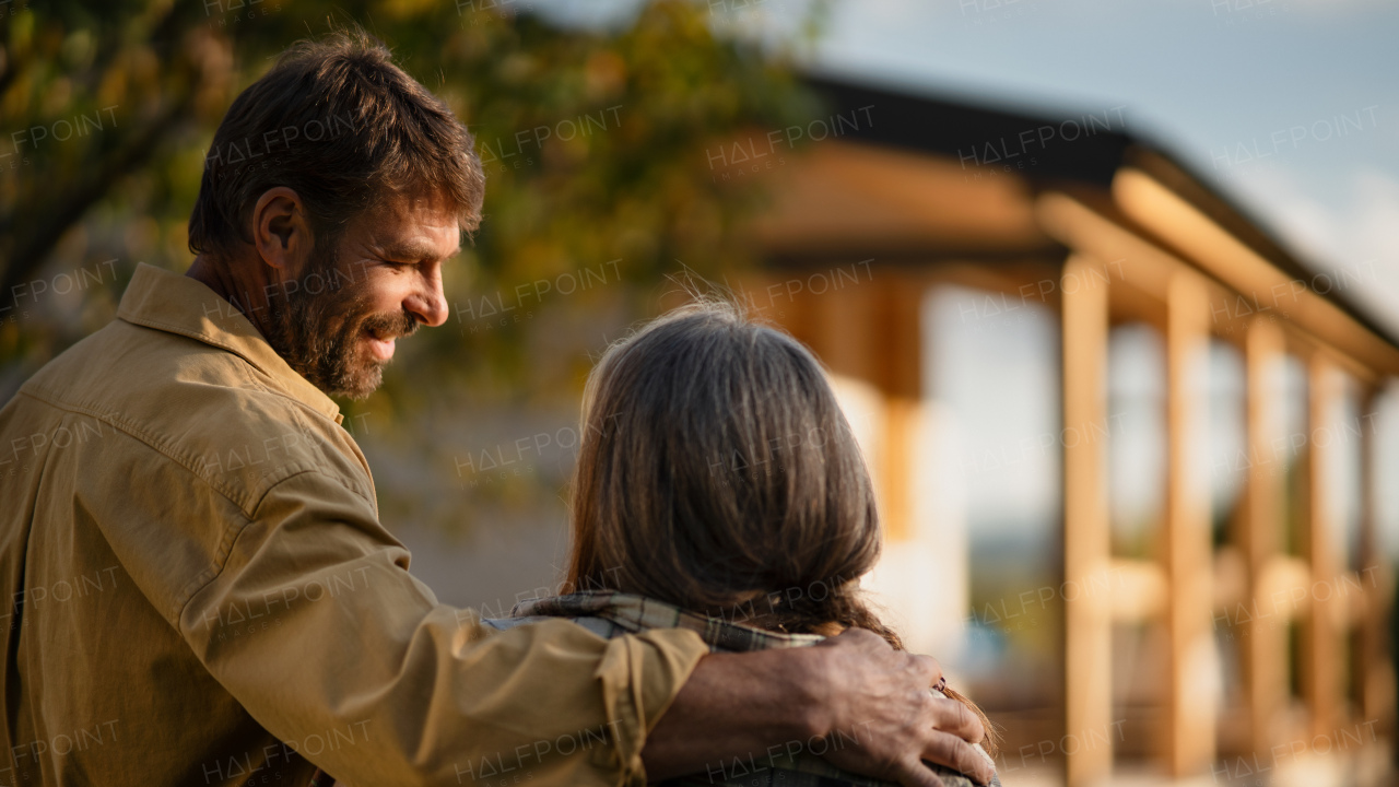 A rear view of mature couple looking at their new house under construction, planning future and dreaming.