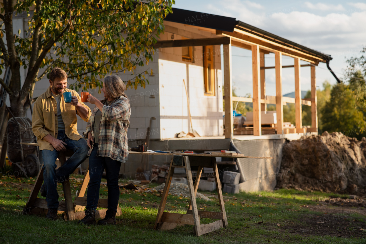 A mature couple having coffee break when working together on construction site of their new house.