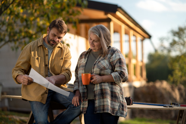 A mature couple having coffee break when working together on construction site of their new house.