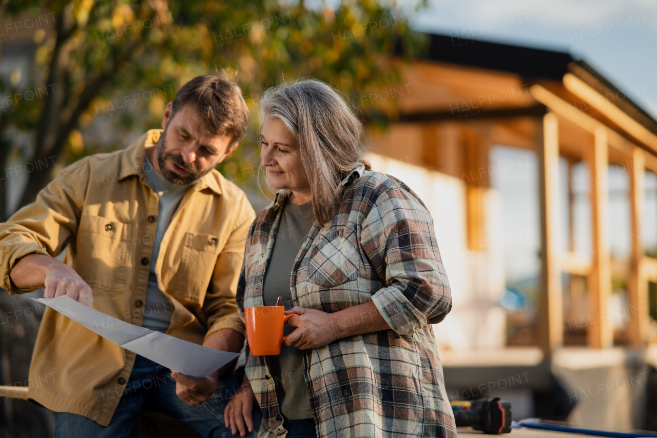 A mature couple having coffee break when working together on construction site of their new house.