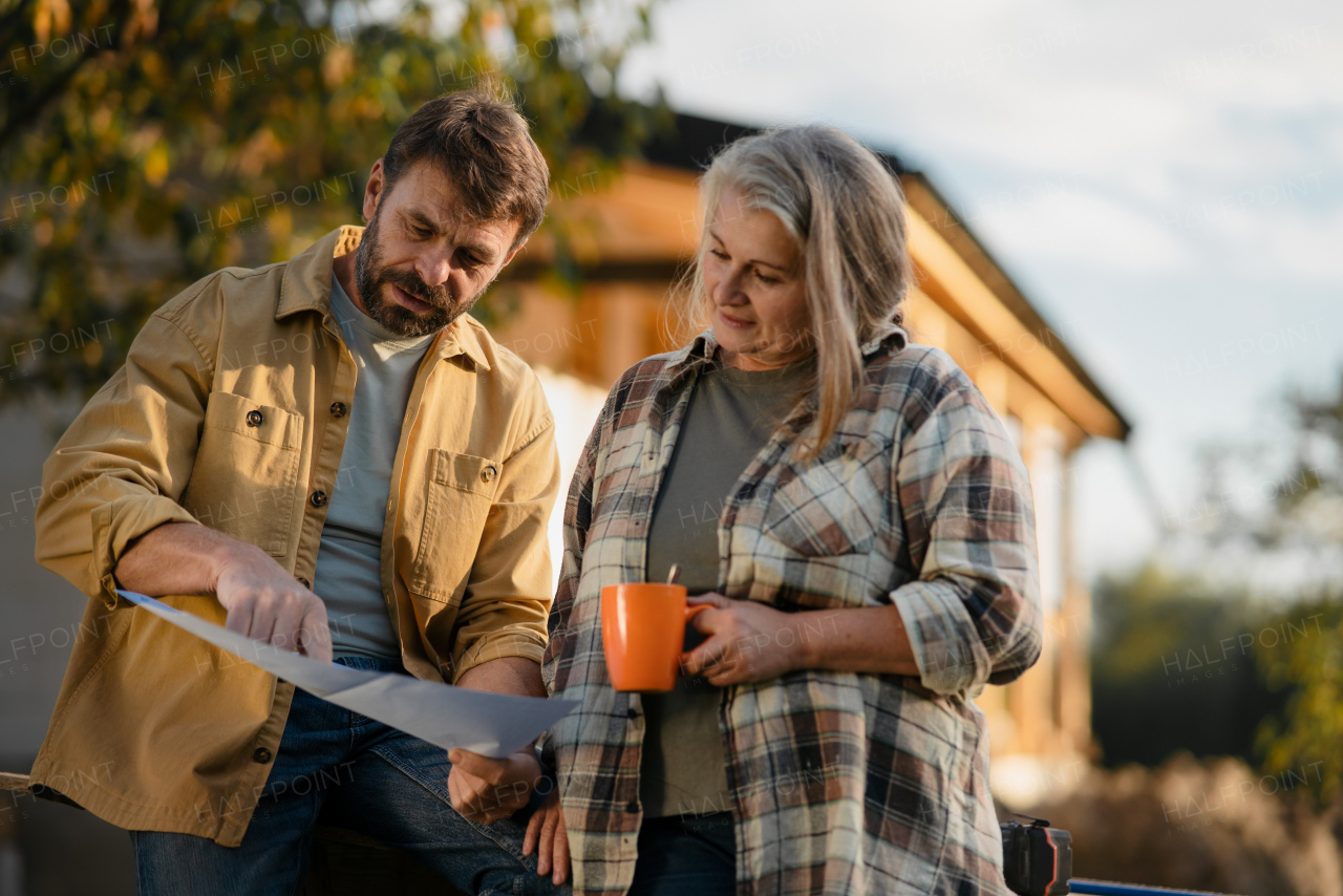 A mature couple having coffee break when working together on construction site of their new house.