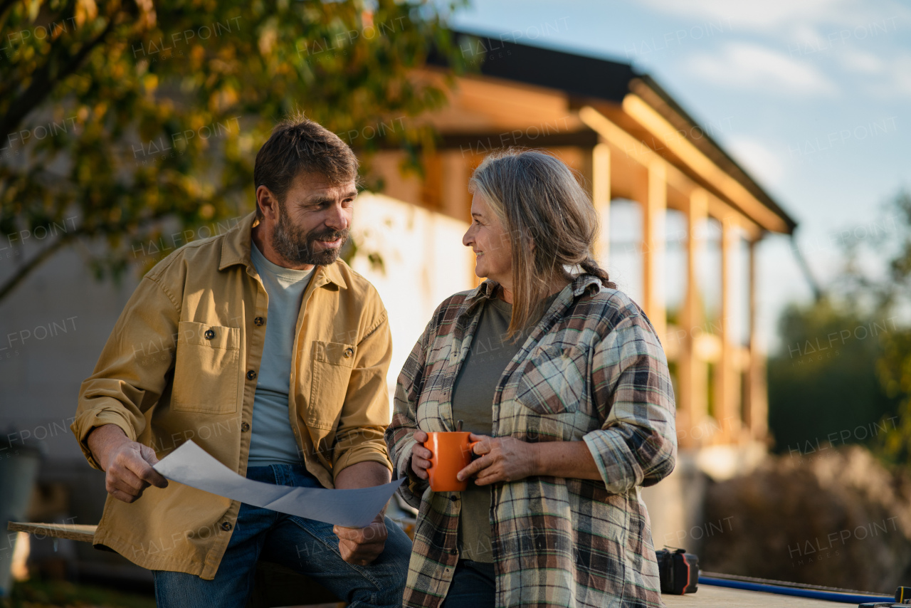 A mature couple having coffee break when working together on construction site of their new house.