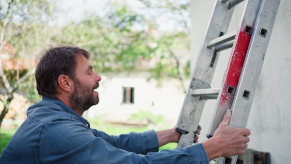 A high angle view of mature man climbing up the ladder