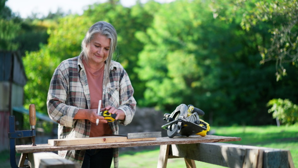 A handy female carpenter working in carpentry diy workshop outdoors