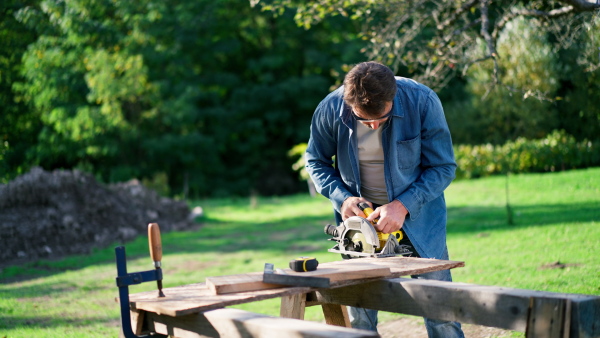 A close-up of craftsman working with circular saw at construction site