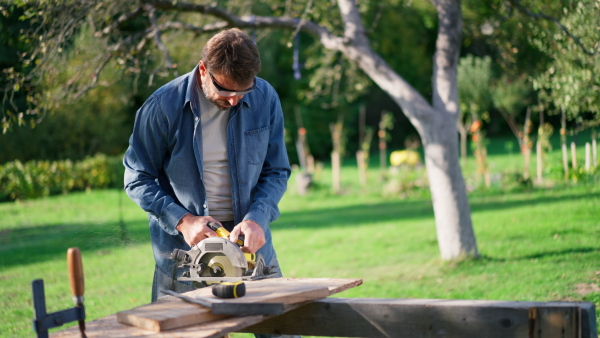 A close-up of craftsman working with circular saw at construction site