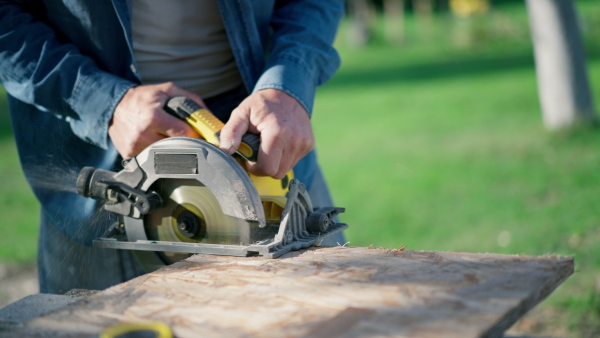 A close-up of craftsman working with circular saw at construction site