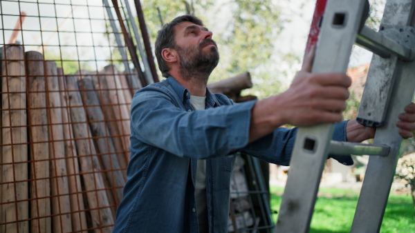 A low angle view of mature man climbing up the ladder