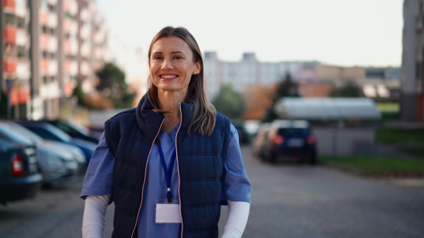 A happy female caregiver outdoors in town looking at camera.