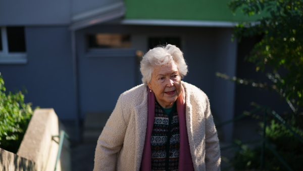 A senior woman walking upstairs in city in winter.