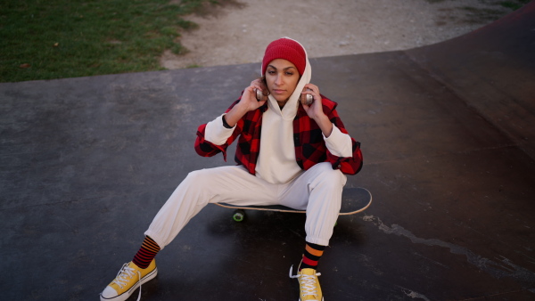 A young multiracial woman outdoors in the city, with skateboard looking at camera.