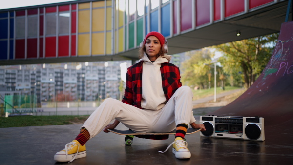 A young multiracial woman outdoors in the city, with skateboard looking at camera.