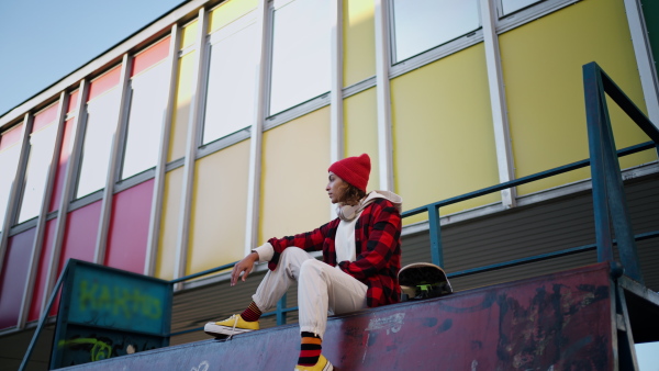 A young multiracial woman outdoors in the city, with skateboard looking at camera.