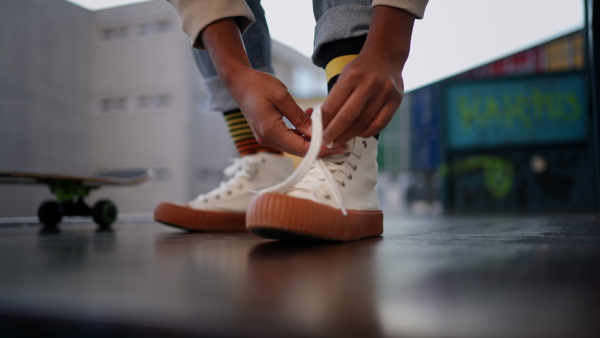 A close-up of modern urban girl tying sneakers in street.