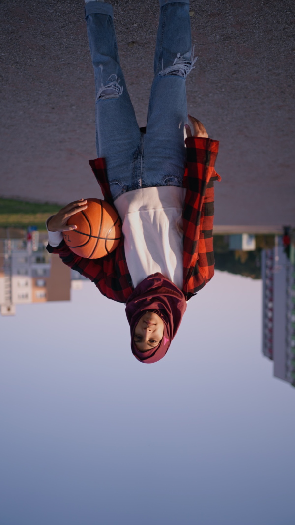 A low angle view of sporty young Muslim woman in hijab exercising outdoors in city, looking at camera.