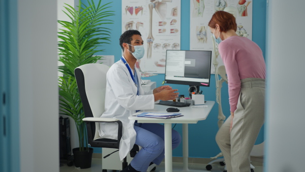 A woman patient at doctor's office on orthopedic consultation, coronavirus concept.