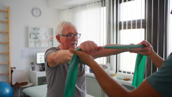 An unrecognizable physiotherapist exercising with senior patient in a physic room