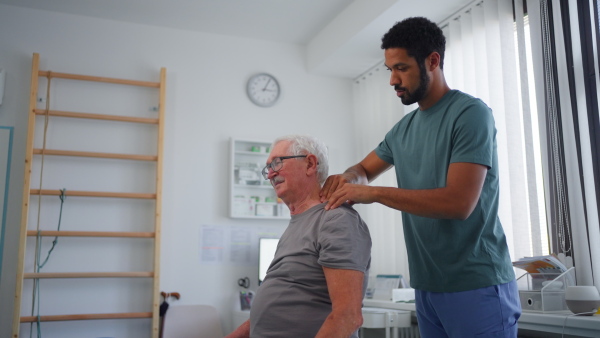 A young physiotherapist massaging the neck of senior patient in a physic room