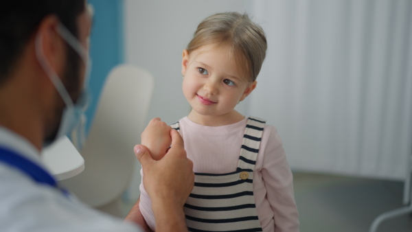 A young male doctor examining little girl in his office.