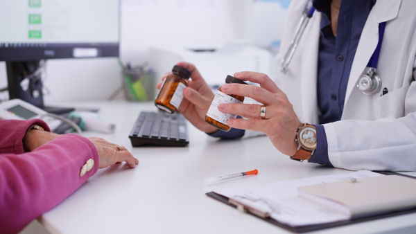 A close-up of senior woman on consultation with doctor in his office, explaining dosage of pills.