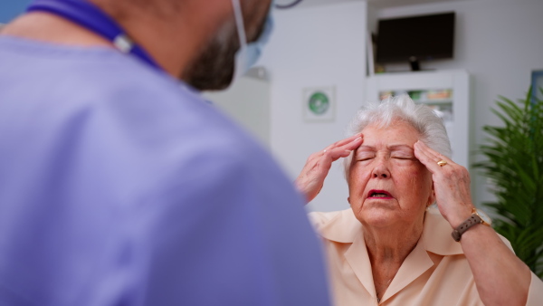 A senior woman patient explaining her problems to doctor in clinic.